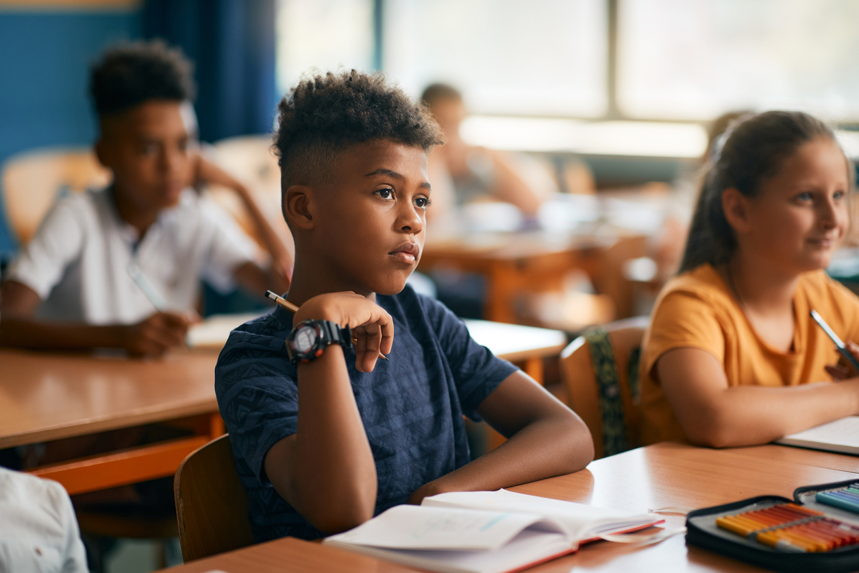 African American schoolboy and his classmates paying attention during a class in the classroom.
