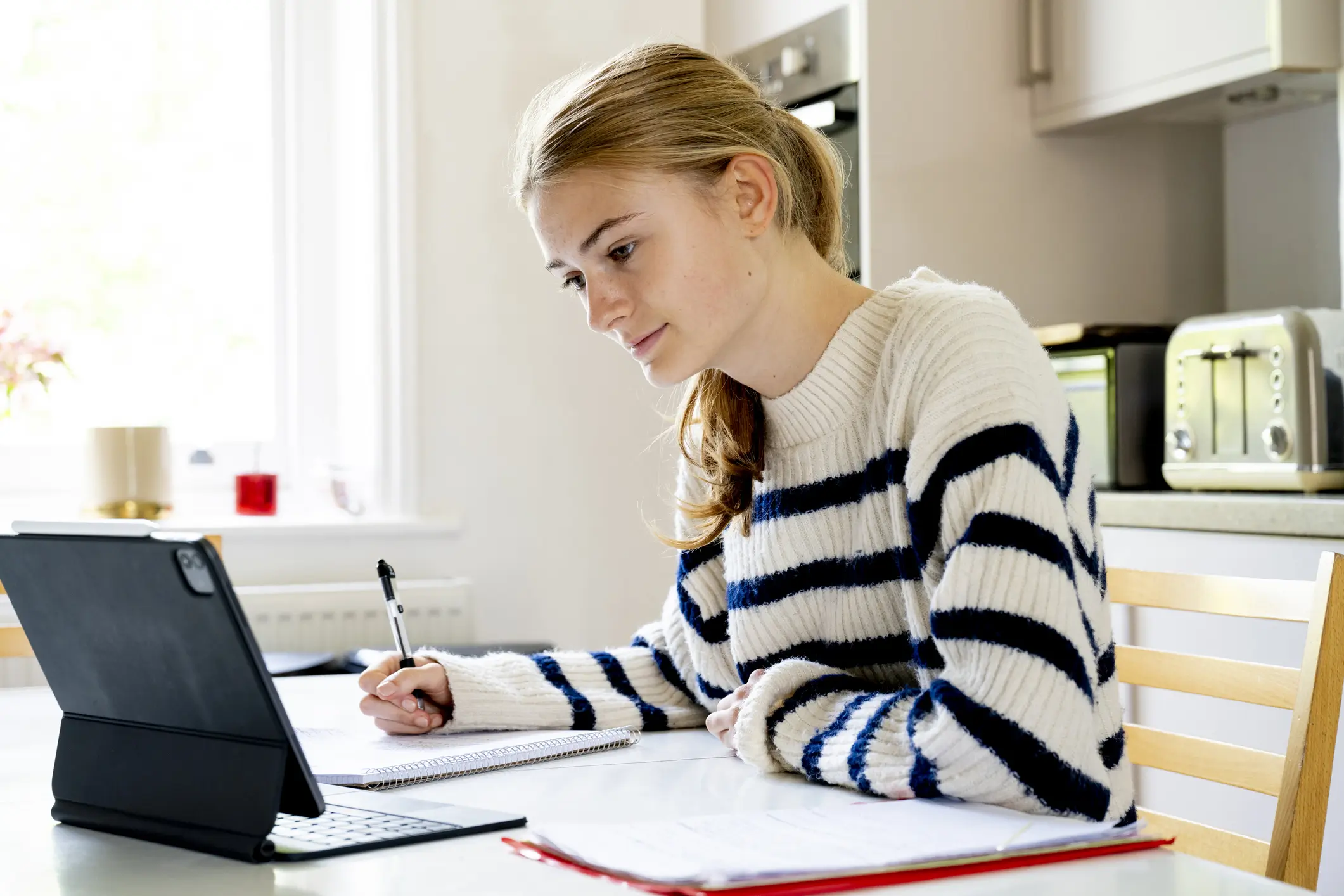 15 year old girl sitting in kitchen doing homework